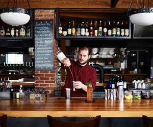 Sam Nelis, original bar manager, making drinks behind the bar