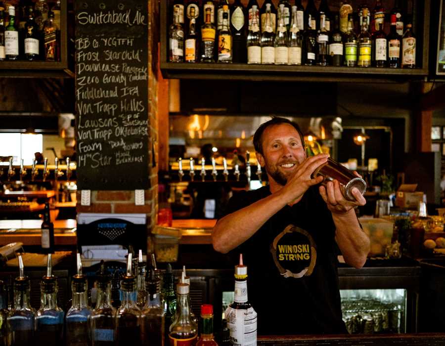 A Waterworks bartender shakes a cocktail from behind the bar.