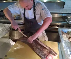 Chef cutting and cleaning a filet of fish