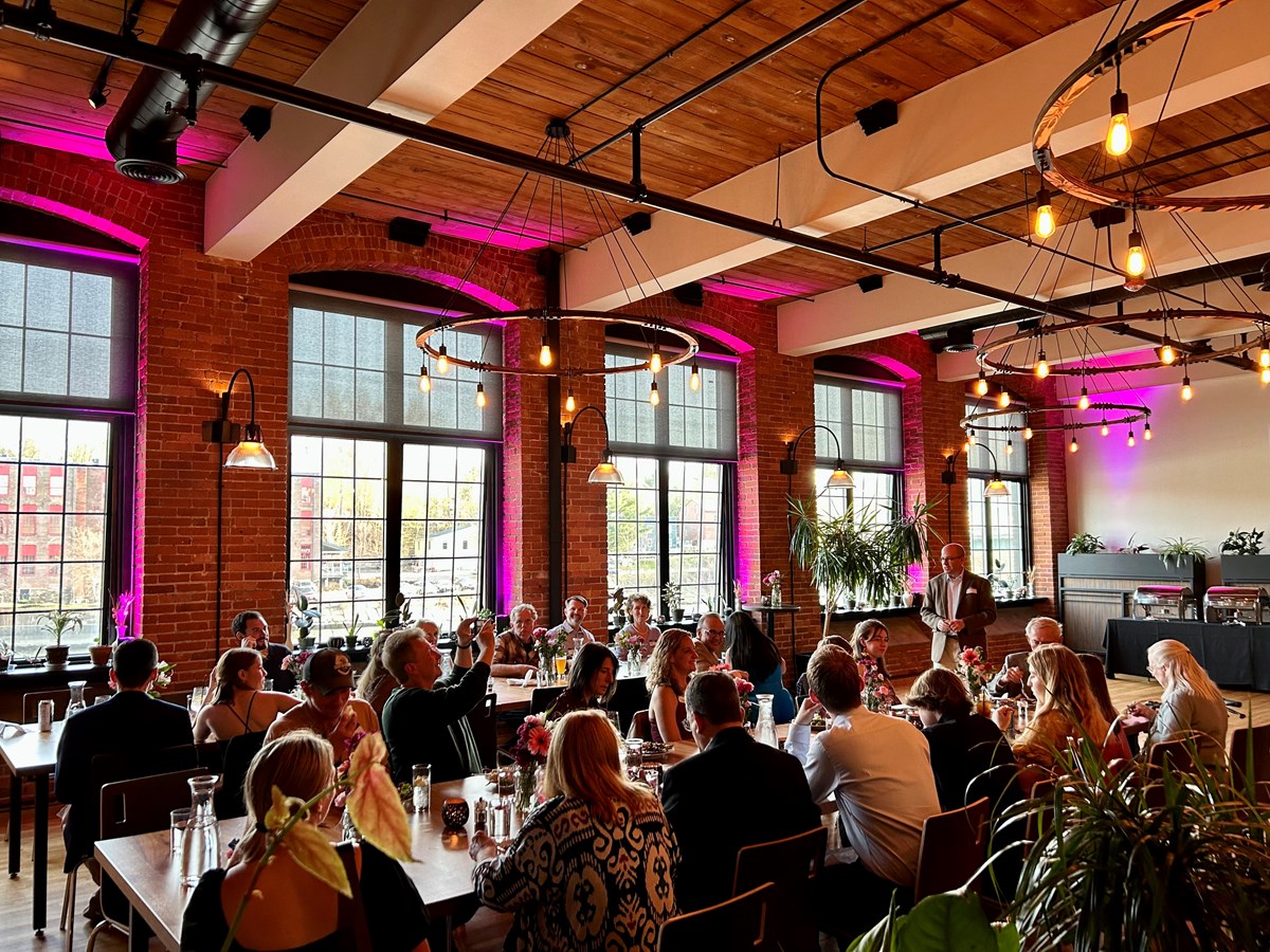 A group of family and friends listen to a speech at a rehearsal dinner in Waterworks' river house