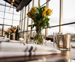 Table setup in the Solarium for a special event with vases of flowers, candles, and folded linen napkins