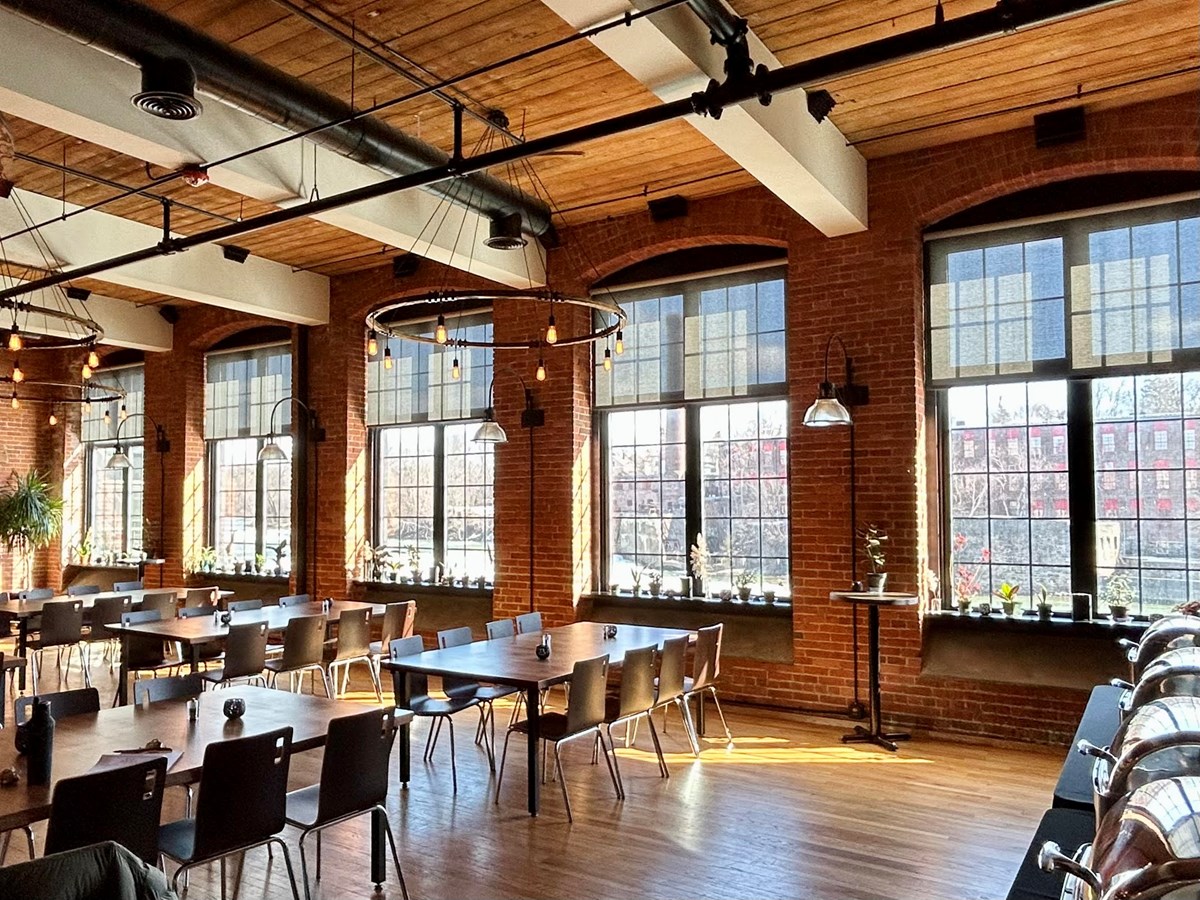 sunlight streams through the wall of windows that open from the River House out to the Winooski River